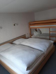 una camera con due letti con lenzuola bianche di Ferienhaus Andrea Höcherl a Wolkenstein