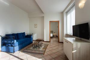 uma sala de estar com um sofá azul e uma televisão em Residenza Cavour em Parma