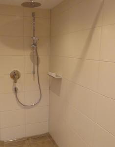 a shower with a hose in a white tiled bathroom at Ferienwohnung Jörg in Bad Hindelang