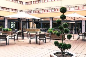 un patio esterno con tavoli, sedie e ombrelloni di ACHAT Hotel Braunschweig a Braunschweig