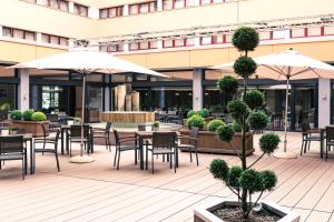patio ze stołami, krzesłami i parasolami w obiekcie ACHAT Hotel Braunschweig w Brunszwiku