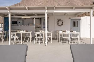 un patio con mesas blancas y sillas blancas en Sagma Beach Rooms, en Perissa