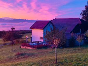 uma casa no meio de um campo com um pôr do sol em La Ferme de la Praz B&B em La Praz