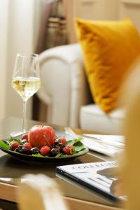 
a glass of wine next to a plate of fruit at Althoff Hotel Fürstenhof in Celle
