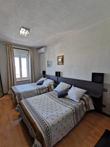 een slaapkamer met 2 bedden en een raam bij l'Hotel du port in Port-la-Nouvelle