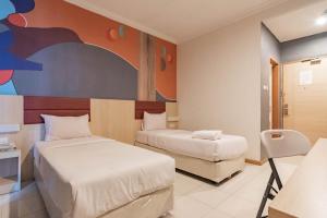 a bedroom with two beds and a painting on the wall at RedDoorz At Hotel Arimbi Dewi Sartika Baru in Bandung +49 photos