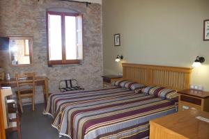 a bedroom with a bed and a table and a window at Hotel Muralleta in Riba-Roja De Turia