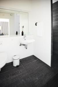 a white bathroom with a sink and a toilet at Haraldskær Sinatur Hotel & Konference in Vejle