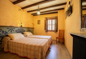 カラタニャソルにあるHotel Rural Calatañazorのベッドルーム1室(ベッド2台、テーブル、窓付)
