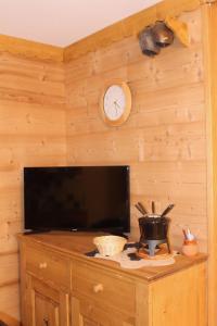 una pared con reloj y TV en una habitación en L'Enclave, en Les Contamines-Montjoie