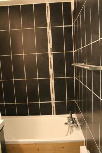 a bathroom with black tiled walls and a bath tub at L'Enclave in Les Contamines-Montjoie +12 photos