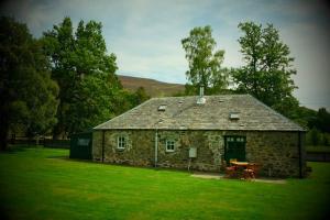 a stone house with a picnic table in a field at Blairbeg Cottage in Blairgowrie