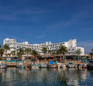 un groupe de bateaux amarrés devant un grand bâtiment dans l'établissement Limanaki Beach Hotel & Suites, à Ayia Napa