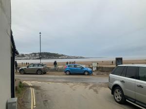 two cars parked in a parking lot next to the beach at Wayfarer Inn in Instow