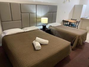 two beds in a hotel room with towels on them at Tollgate Motel in Adelaide