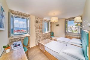a bedroom with two beds and a table and windows at Luxury Residence Mladenka in Jesenice