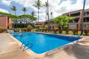 een zwembad voor een gebouw met palmbomen bij Kuleana Resort 207 in Kahana