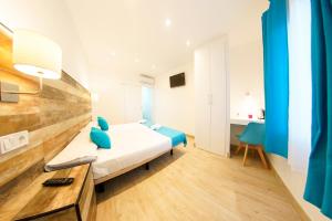 a bedroom with a bed with blue pillows and a table at Hotel Zen Airport in Torremolinos