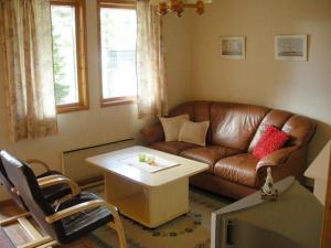 a living room with a brown leather couch and a table at Marbyfjärden seaside village Lyckan in Eckerö