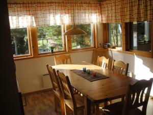 a dining room with a wooden table and some windows at Marbyfjärden seaside village Lyckan in Eckerö