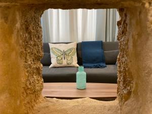 - un canapé avec un oreiller en papillon et une bouteille sur une table dans l'établissement GADEIRAS SUITES - Apartamentos Turísticos de 2 llaves, à Cadix