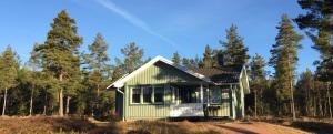 a green house in the middle of a forest at Marbyfjärden seaside village Lyckan in Eckerö