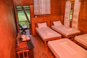 a room with two beds and a balcony at Cinnamon Village Sinharaja in Deniyaya