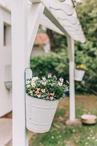 a flower pot hanging from a porch rail with flowers at Csónakos ház / The boat house in Badacsonyörs