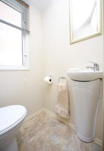 Baño blanco con aseo y lavamanos en Newquay Bay Resort 151, en Newquay