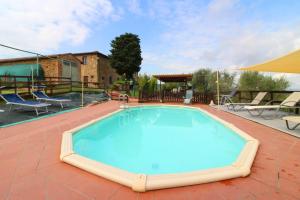 a large swimming pool on a brick patio with chairs at Casa Bella in Torrita di Siena