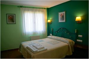 zieloną sypialnię z łóżkiem i ręcznikami w obiekcie Casa Rural La Casa Nueva de Abejar w mieście Abejar