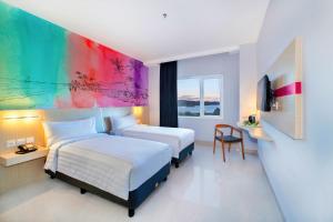 a hotel room with two beds and a colorful wall at favehotel Bitung in Bitung