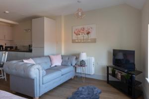 a living room with a blue couch and a tv at Hereford City Centre - Apartment 9, Isabella House - Modern Apartment In The Heart of The City - Sleeps 4 Guests - Hosted by RENTMYHOUSE in Hereford