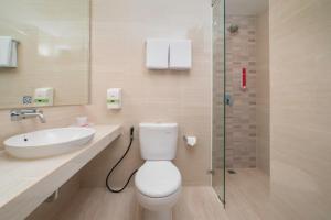 a bathroom with a toilet and a sink and a shower at favehotel Bitung in Bitung