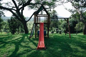 a swing set in a park with a tree at Rockview Lodge in Nelspruit