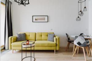 sala de estar con sofá amarillo y mesa en Apartment4You Select Kolejowa, en Varsovia