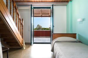 a bedroom with a bed and a sliding glass door at Vasilikos Garden Suites in Vasilikos