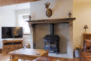 a living room with a fireplace and a tv at 5 Star Cottage on the Green with Log Burner - Dog Friendly in Austwick
