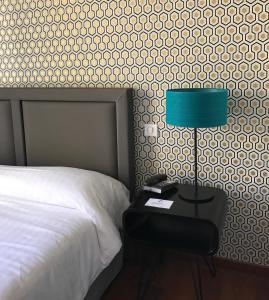 1 dormitorio con 1 cama y 1 mesa con lámpara en Le Grand Hotel, en Sète