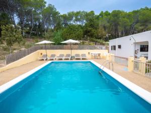 a pool with chairs and umbrellas next to a house at Holiday Home Can Fulgencio II by Interhome in Cala Llenya