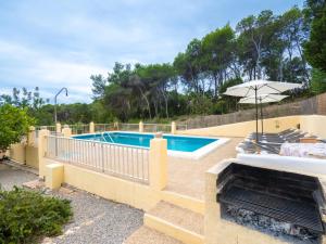 a swimming pool with an umbrella and chairs and an umbrella at Holiday Home Can Fulgencio II by Interhome in Cala Llenya