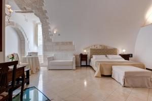 オストゥーニにあるホテル ラ テラのベッド2台、テーブルと椅子が備わるホテルルームです。