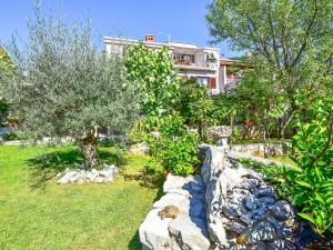 a garden with a stone wall and trees and a building at Apartment Damir-3 by Interhome in Crikvenica