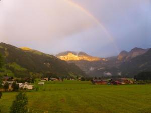 a rainbow over a green field with mountains at Apartment Chalet Claudia by Interhome in Lenk