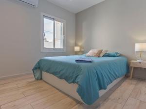 een slaapkamer met een bed met een blauwe deken en een raam bij Holiday Home Sangha by Interhome in Empuriabrava