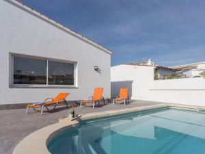 een zwembad met twee stoelen en een huis bij Holiday Home Sangha by Interhome in Empuriabrava