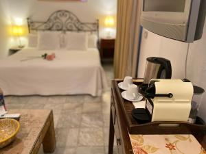 a hotel room with a bed, table, dresser and mirror at La Casa del Maestro Boutique in Seville