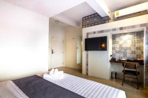 a hotel room with a bed and a desk at Montree Phuket Hotel in Phuket Town