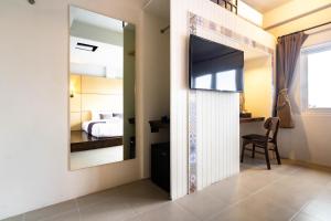a room with a mirror and a tv on a wall at Montree Phuket Hotel in Phuket Town