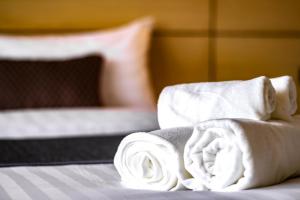 a pile of towels on top of a bed at Montree Phuket Hotel in Phuket Town